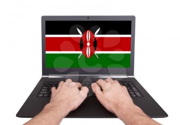Hands working on laptop showing on the screen the flag of Kenya