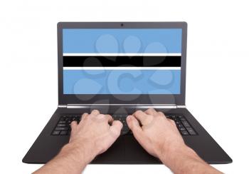 Hands working on laptop showing on the screen the flag of Botswana