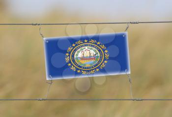 Border fence - Old plastic sign with a flag - New Hampshire
