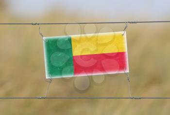 Border fence - Old plastic sign with a flag - Benin