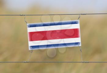 Border fence - Old plastic sign with a flag - Costa Rica