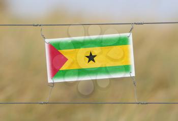 Border fence - Old plastic sign with a flag - Sao Tome and Principe