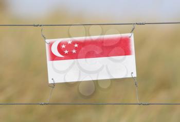 Border fence - Old plastic sign with a flag - Singapore
