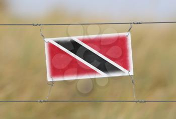 Border fence - Old plastic sign with a flag - Trinidad and Tobago