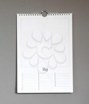 Simple old birthday calendar hanging on a grey wall, copy space - May