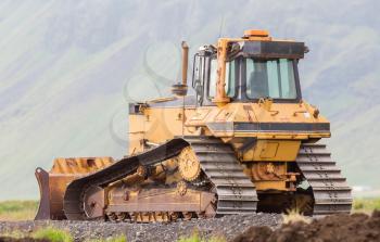 Yellow bulldozer in the field, construction in Iceland