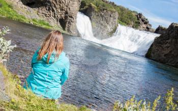 Woman sitting at a waterfall in Iceland