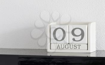 White block calendar present date 9 and month August on white wall background