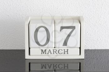 White block calendar present date 7 and month March on white wall background