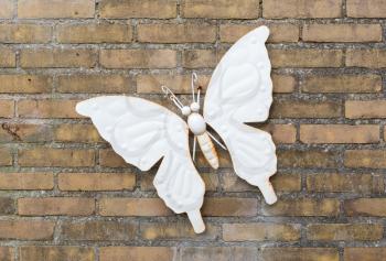Large white rusty butterfly hanging on a brick wall
