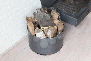 Metal basket of firewood, standing next to a fireplace