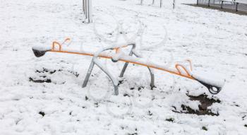 Modern steel seesaw in the village playground - Covered in snow