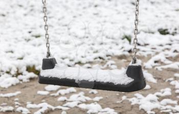 Empty swing in playground - Covered in snow
