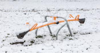 Modern steel seesaw in the village playground - Covered in snow