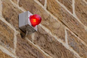 Red warning light on a brick wall