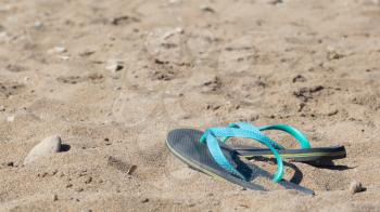Blue and green flip flops in the sand