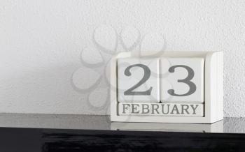 White block calendar present date 23 and month February on white wall background