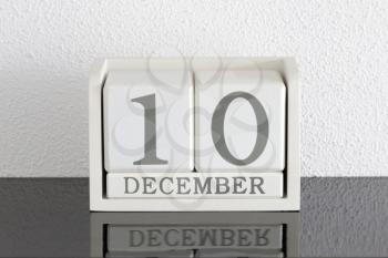White block calendar present date 10 and month December on white wall background