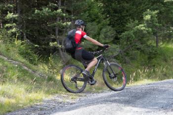 Urecognisable mountainbiker on a gravel road in the Alps