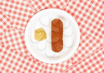 Brown crusty dutch kroket with mustard on a white plate isolated on a white background