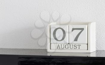 White block calendar present date 7 and month August on white wall background