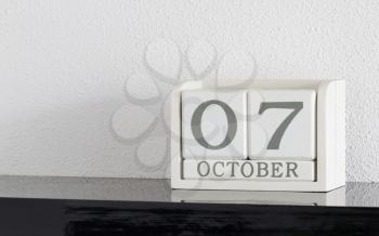White block calendar present date 7 and month October on white wall background