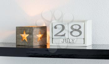 White block calendar present date 28 and month July on white wall background