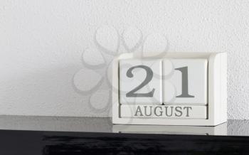 White block calendar present date 21 and month August on white wall background