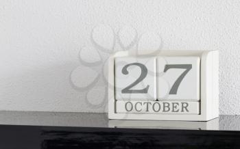 White block calendar present date 27 and month October on white wall background