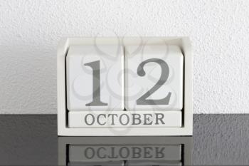 White block calendar present date 12 and month October on white wall background