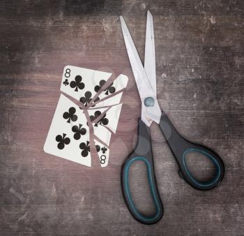 Concept of addiction, card with scissors, eight of clubs