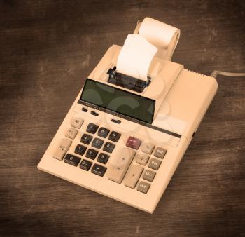 Old dirty calculator on a wooden desk - warm yellow filter