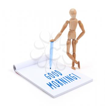 Wooden mannequin writing in a scrapbook - Good morning