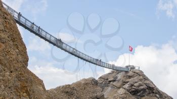 LES DIABLERETS, SWIZTERLAND - JULY 22: People walk at the Glacier 3000 on July 22, 2015. The area houses the world only suspension bridge between 2 mountain peaks.