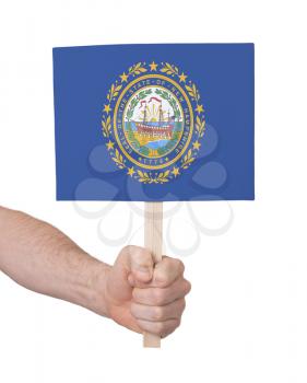 Hand holding small card, isolated on white - Flag of New Hampshire