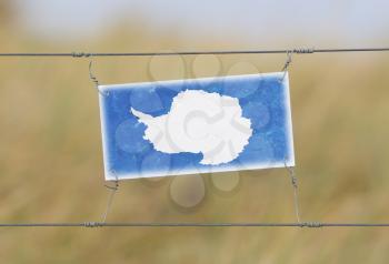 Border fence - Old plastic sign with a flag - Antarctica