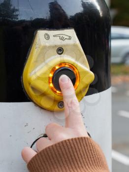 Female hand pushing button for traffic light