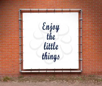 Large banner with inspirational quote on a brick wall - Enjoy the little things