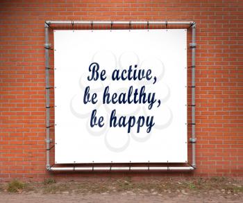 Large banner with inspirational quote on a brick wall - Be active, be healthy, be happy