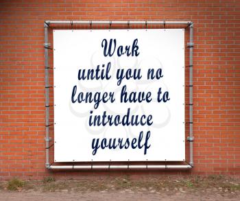 Large banner with inspirational quote on a brick wall - Work until you no longer...