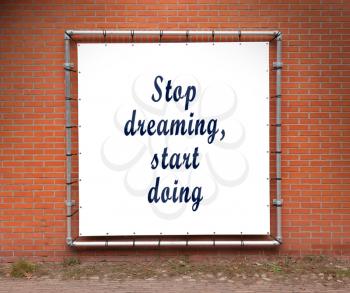 Large banner with inspirational quote on a brick wall - Stop dreaming, start doing