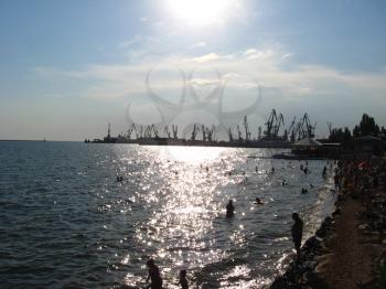panorama of the evening sea with docks and swimming people