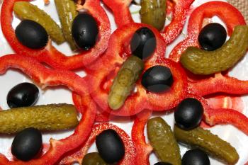 Black olives, marinaded cucumbers and cut paprika on the plate