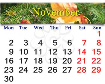 calendar for November of 2015 with the ribbon of yellow dry leaf on the evergreen spruce