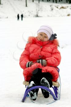 pretty girl sitting on the sledge in the red feather bed