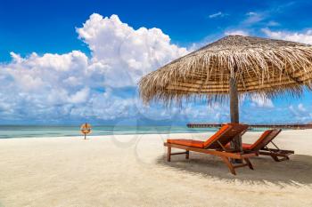 MALDIVES - JUNE 24, 2018: Wooden sunbed and umbrella on tropical beach in the Maldives at summer day