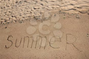 Summer text is written on wet warm sand