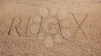Relax text is written on wet warm sand