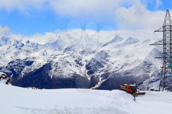 Winter landscape of Caucasus mountains with snowplow machine