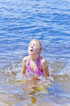 Jumping girl in pink swimsuit with droplets of water